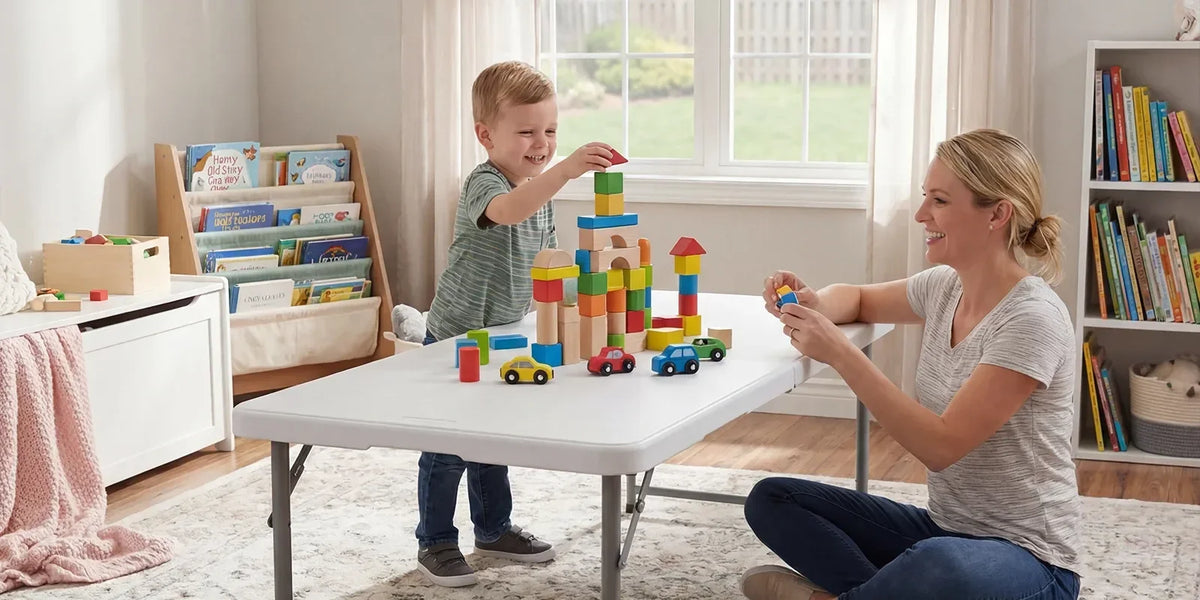 Child and parent building with blocks on a low adjustable folding table in a bright family room.